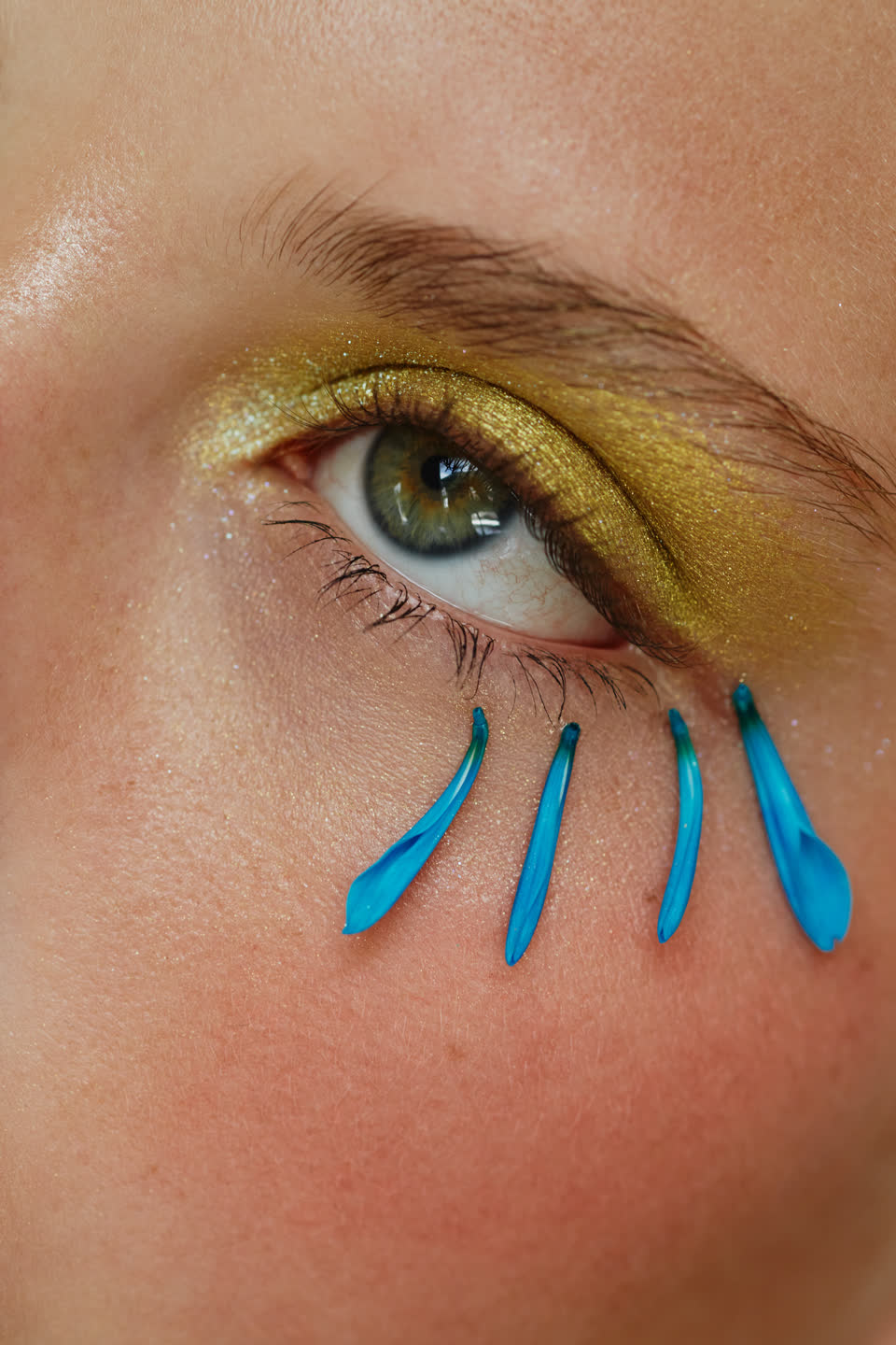 Ojo con sombra dorada y pétalos azules — editorial Clarena Makeup